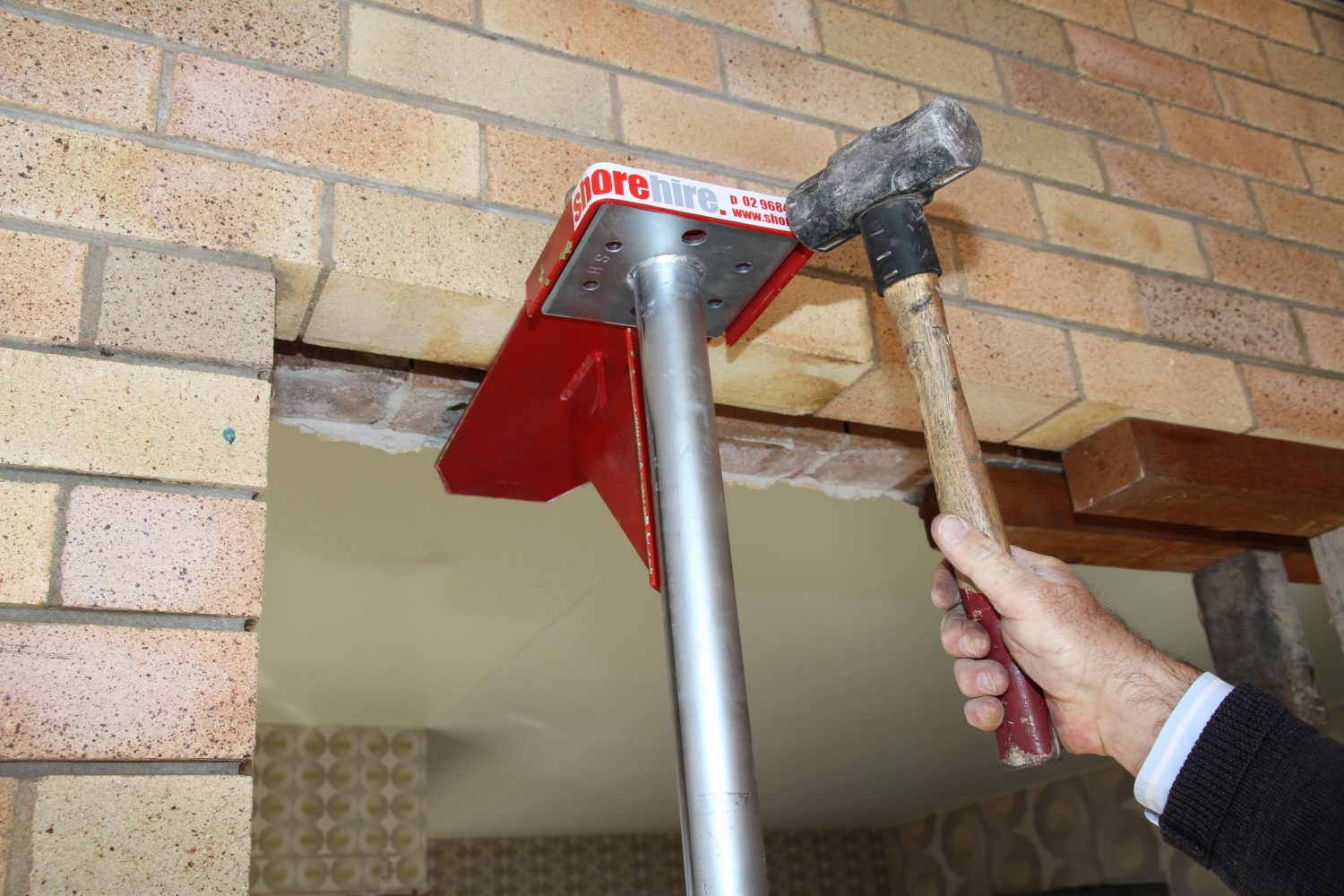 A person hammering a Strong Boy into a brick wall